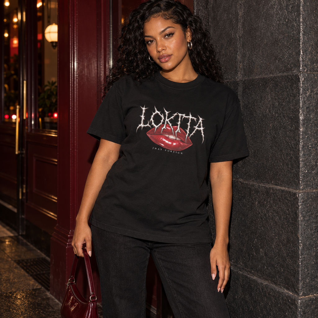 Styled model mockup of the black LOKITA Lip Bite Heavyweight Tee with red lips, spiky lettering and Jhay Foreign signature.