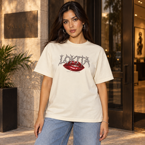 Styled model mockup of the Ivory LOKITA Lip Bite Heavyweight Tee with red lips, spiky lettering and Jhay Foreign signature.